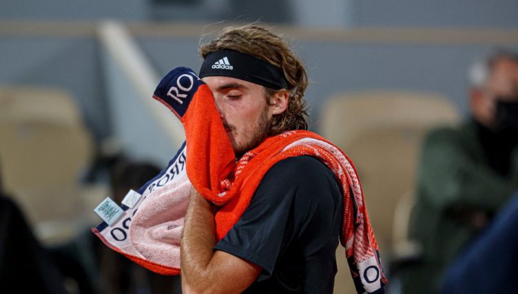 Stefanos Tsitsipas wipes his face