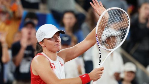 Iga Swiatek waves to the crowd after victory at Paris 2024.